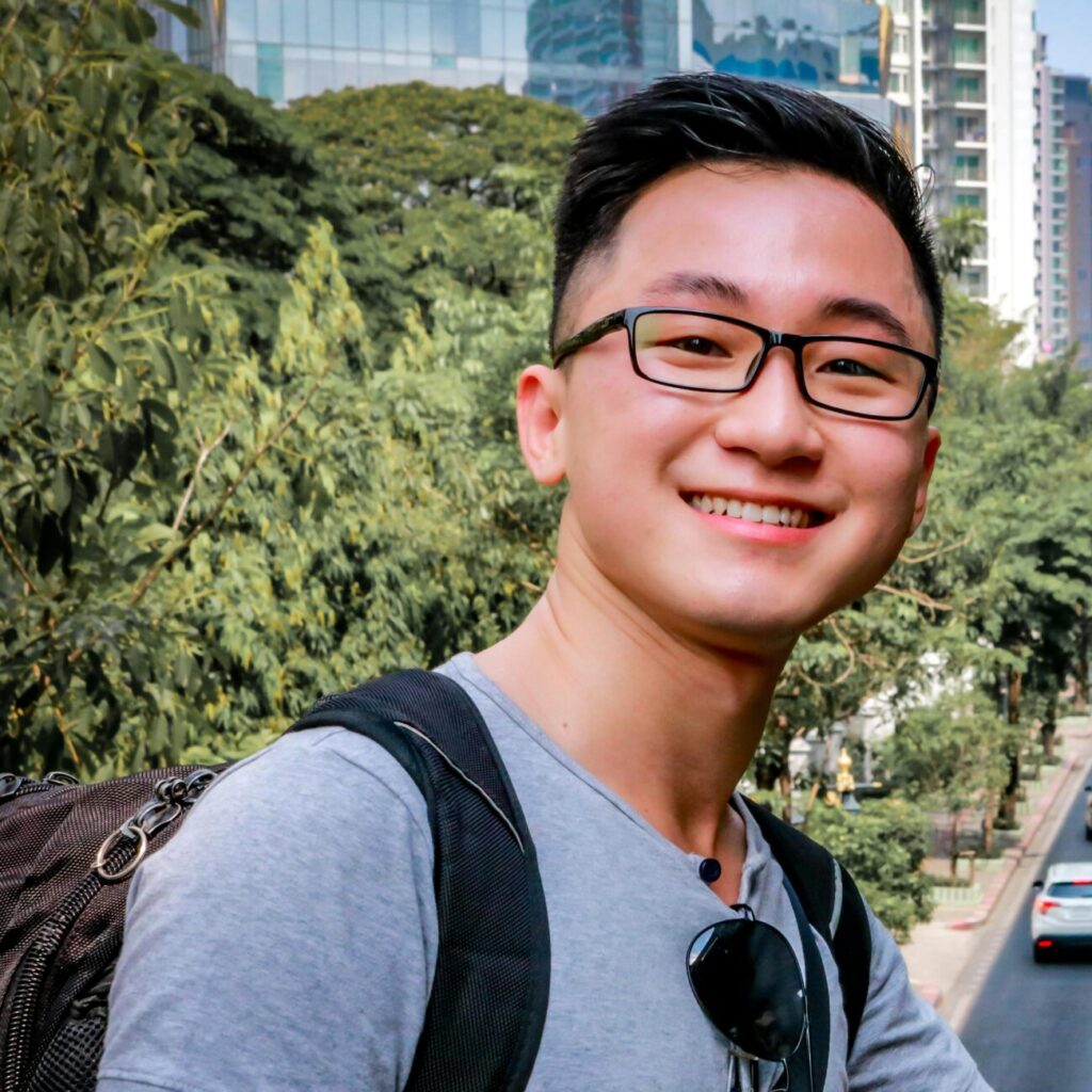 Smiling Asian man on a bridge overlooking urban traffic in Bangkok, Thailand.